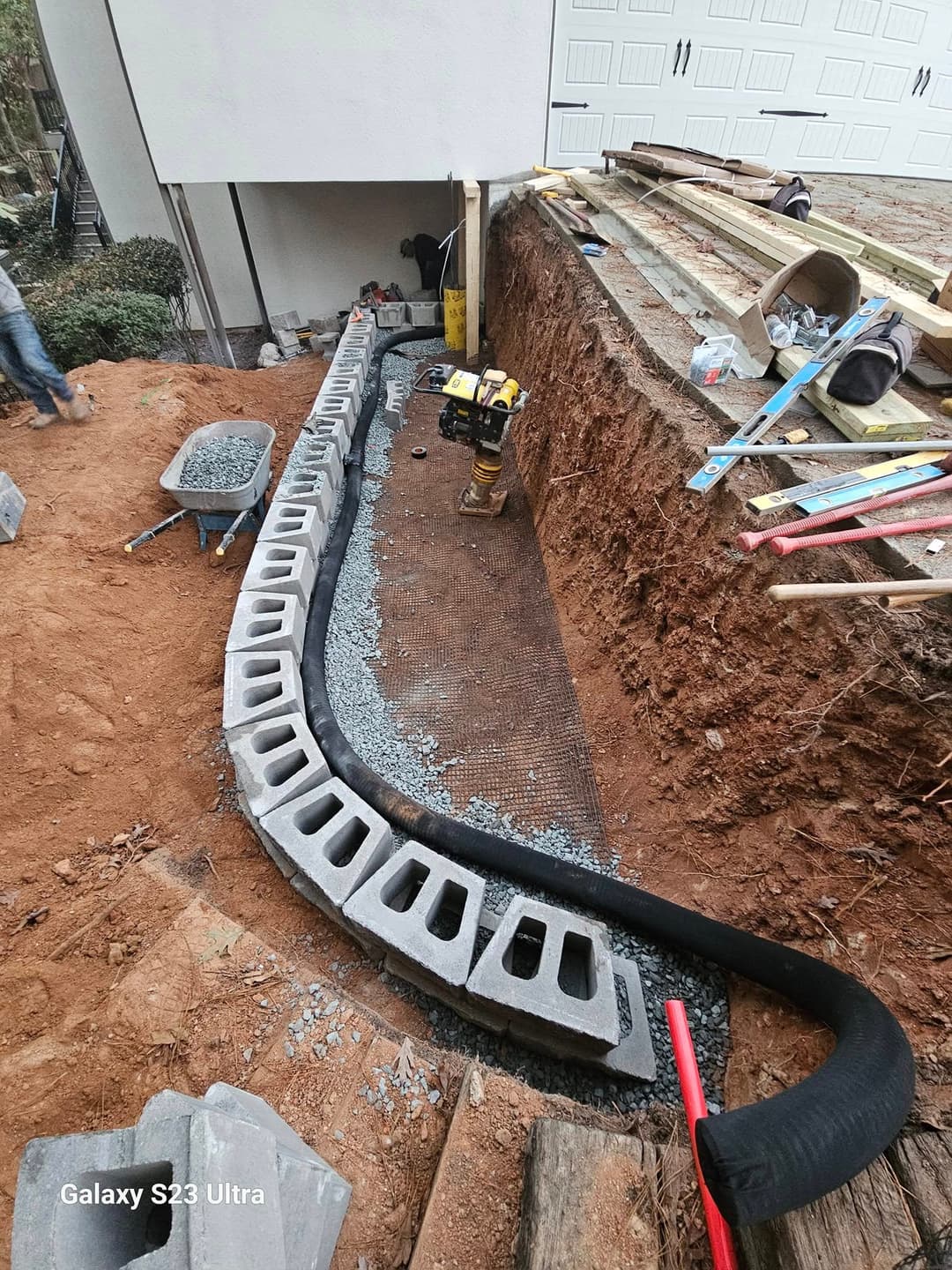 Excavated site featuring a concrete drainage system and construction tools.