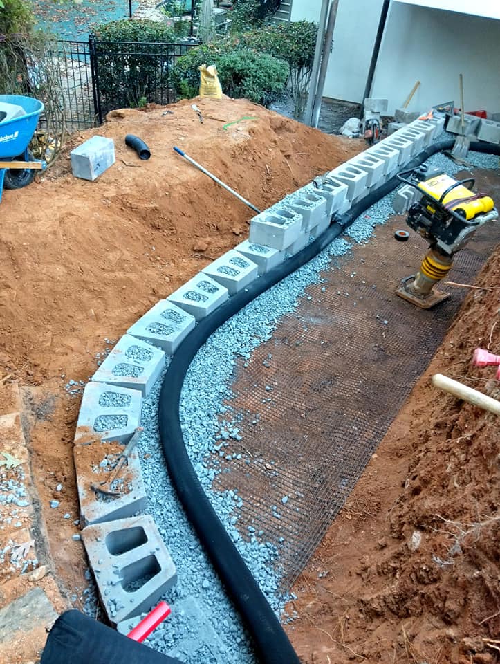 Construction site with a curved concrete block foundation and gravel preparation.